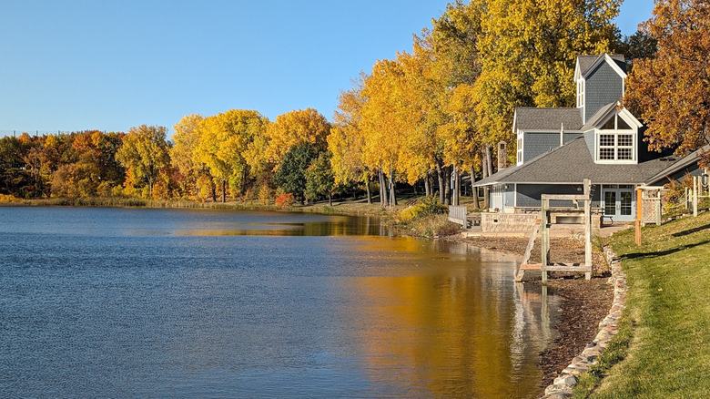 The park building and lifeguard chair at Parkers Lake Park in Plymouth, lined by fall foliage