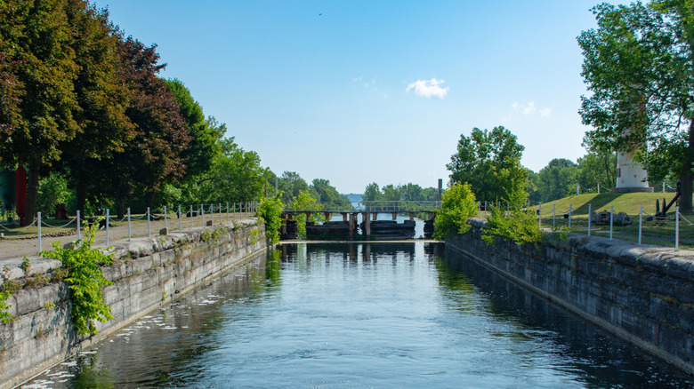 View of a historic lock on the Soulanges Canal, with a lighthouse on the right and trees on the left.