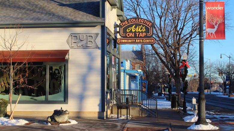 A neon sign for a community arts center on a snowy street in Lafayette, Colorado