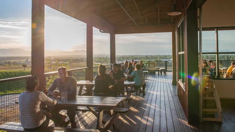 People sit at picnic tables on the balcony of a restaurant