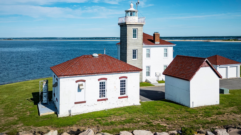 Lighthouse in Rhode Island surrounded by red and white buildings