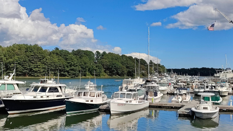Boats in shimmering water beneath puffy clouds, with trees in the background, near Yarmouth, Maine