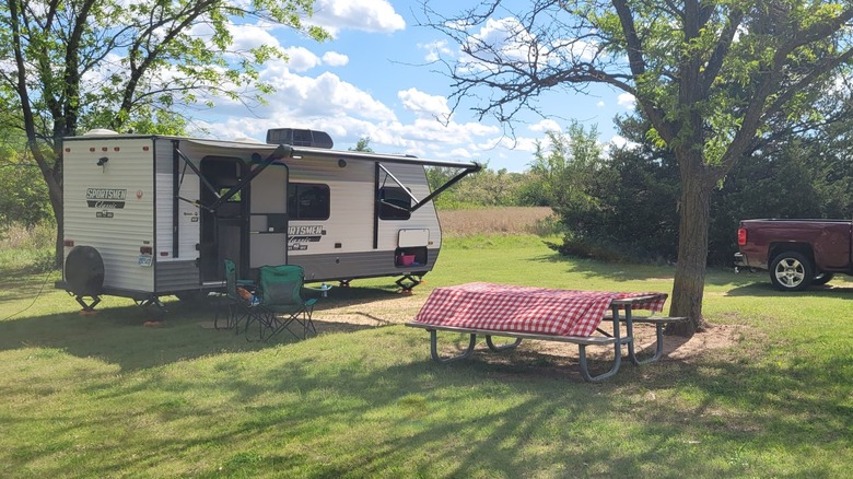 A trailer parked at a grassy campsite at the Cheney State Park campground, with a picnic table beside the vehicle