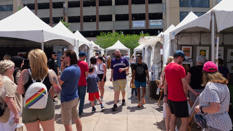 People walking between white tents at the Lenexa Art Festival