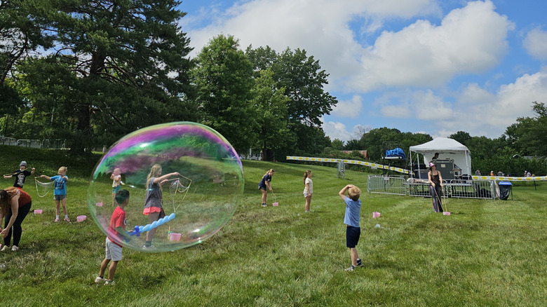 Kids playing with giant bubbles on a lawn at Old Shawnee Days.