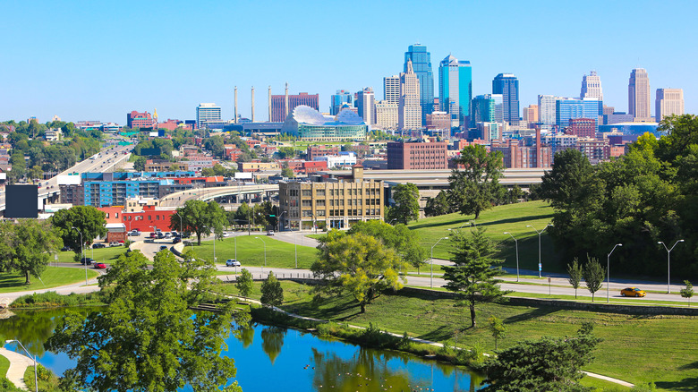 Skyline of Kansas City on summer day with pond and park in foreground.