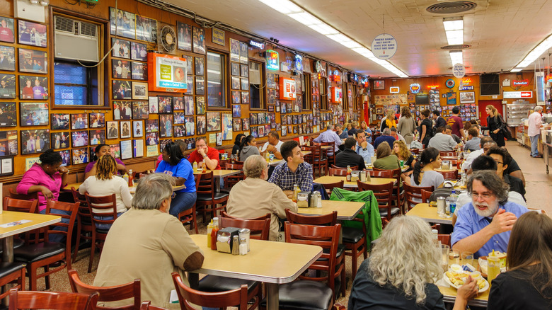 Interior of Katz's Delicatessen with people sitting at restaurant tables, crowded wall decorations