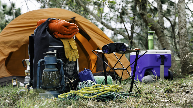 Mountain camping gear in front of a durable orange tent in the winter.