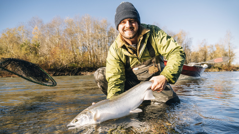 A young man holds a chrome steelhead in a river in Washington State