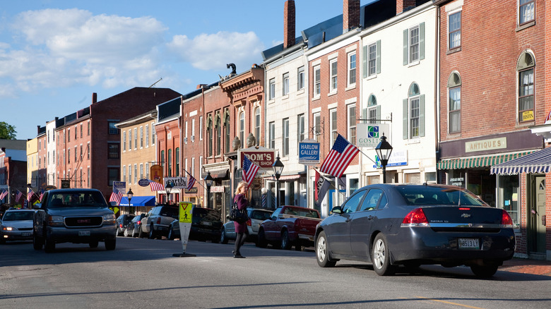 Several shops lining a car-filled street in Hallowell on a bright day in Hallowell County, Maine