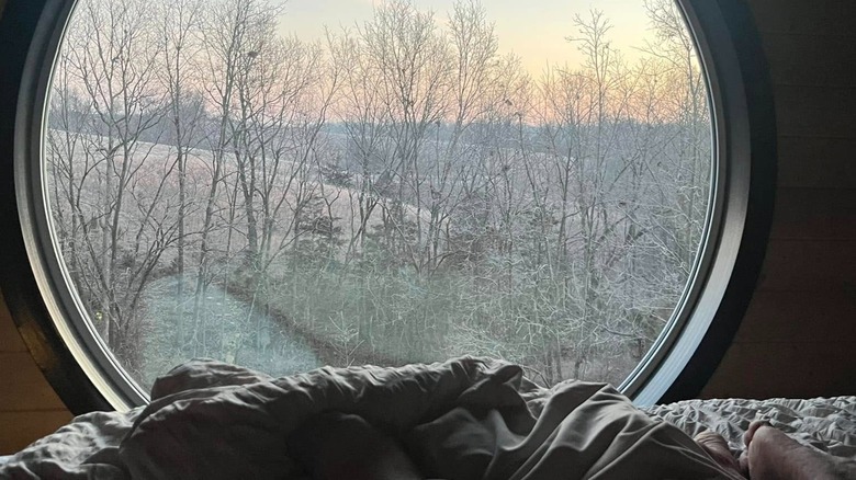 A large, circular window looks out on wintery woods at Bourbon Barrel Retreats.