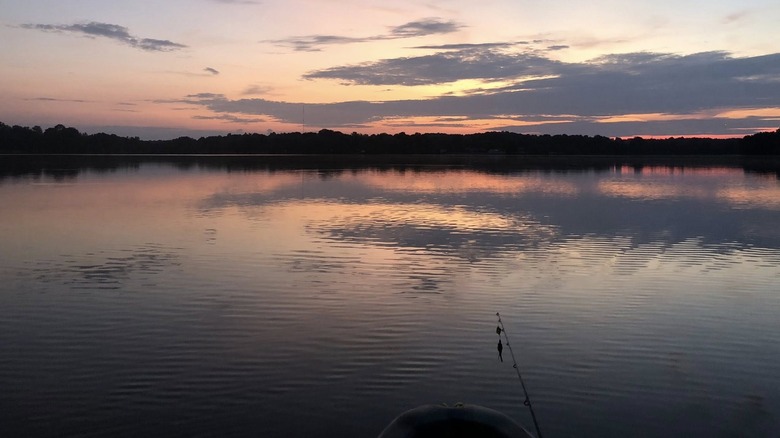 Fishing pole above the water on Lake Peewee in Madisonville at sunset.
