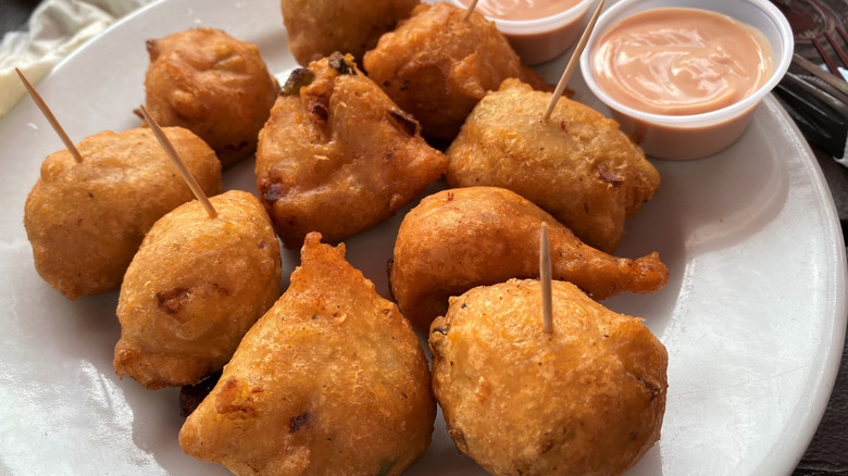 Conch fritters on a plate with dipping sauce