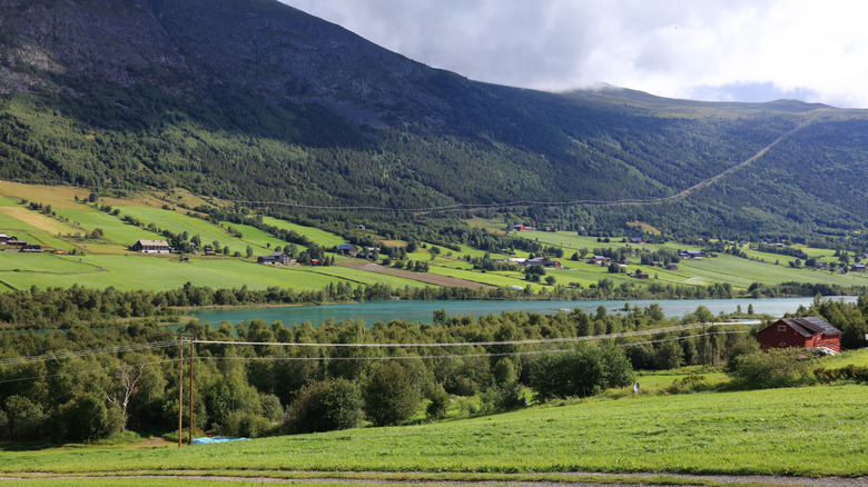 houses in distance with mountain and lake view in valley in Gudbrandsdalen region of Norway