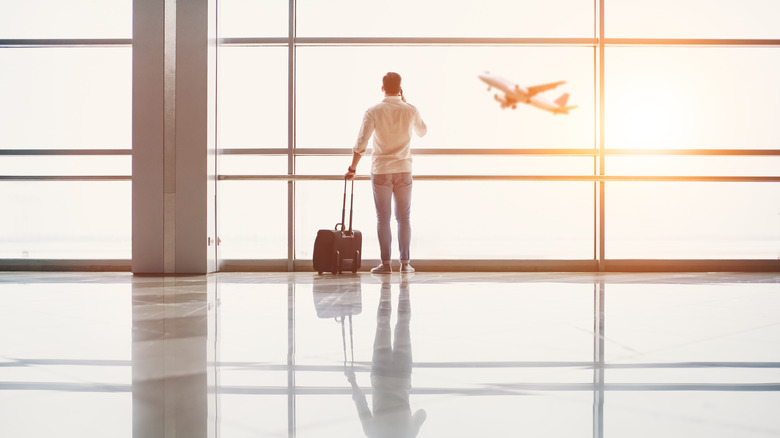Traveler looking out the window at a plane taking off