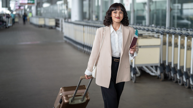 Person walking through an airport with a suitcase