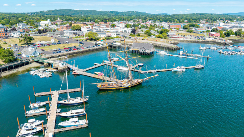 Aerial view of the turquoise waters and tree-lined streets of Rockland, Maine, in Knox County, with rolling hills in the background