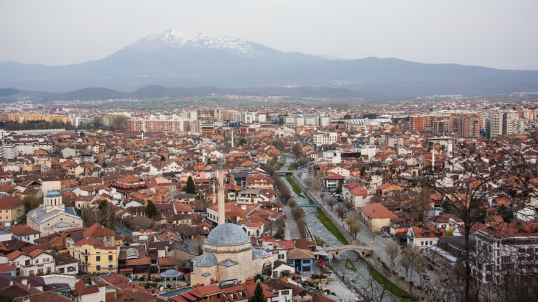 A high angle view of the town of Prizren with Sinan Pasha Mosque, the stone bridge over the eponymous river and the snow-capped Sharr Mountains in the distance, seen from the Fortress in southern Kosovo.