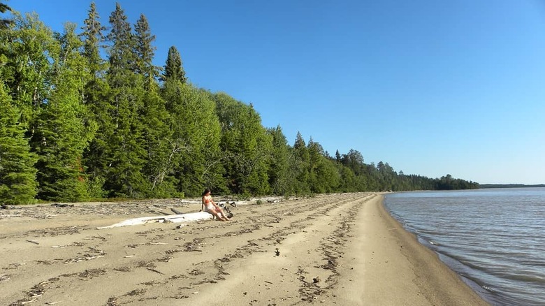 A woman relaxes on the beach at Lake Abitibi