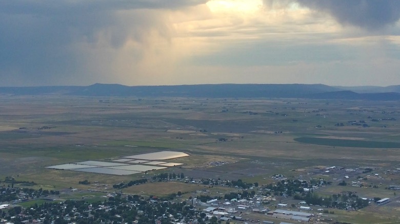View of Lakeview, Oregon, as seen from nearby hills, with fields all around and rain clouds in the distance