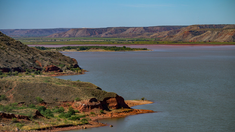 Panoramic view of a calm Lake Meredith, with rocky outcrops that jut into the lake and tall breaks.
