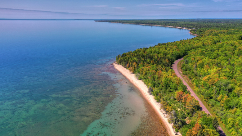 An aerial photo of the Keweenaw Peninsula with another small strip of sand, forest, and a small road cutting through