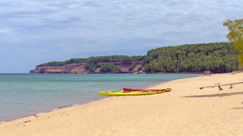 Sandy Miners Beach with two bright kayaks in the center and the Pictured Rocks cliffs in the distance