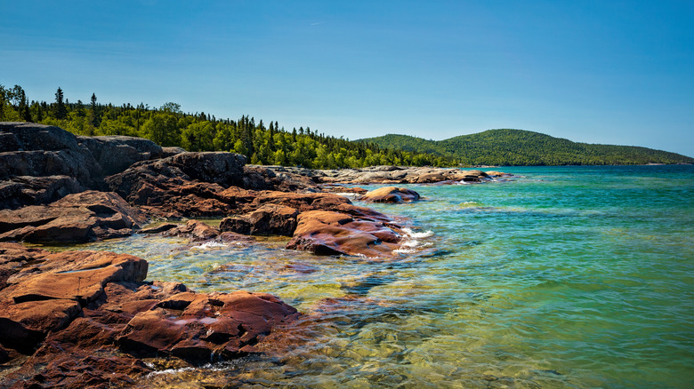 The rocky shores and crystal clear water of Lake Superior at Neys Provincial Park, with pine forests behind