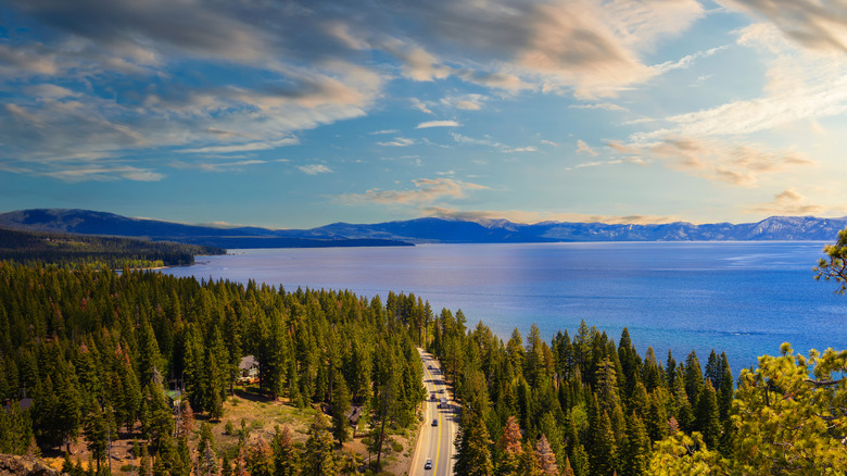 Ariel shot of Lake Tahoe at sunset along a drive by the shore with mountains in the background