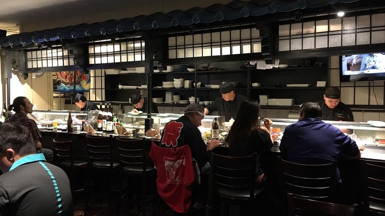 The interior of Osaka Japanese Bistro in Las Vegas, with diners seated at a bar with working chefs