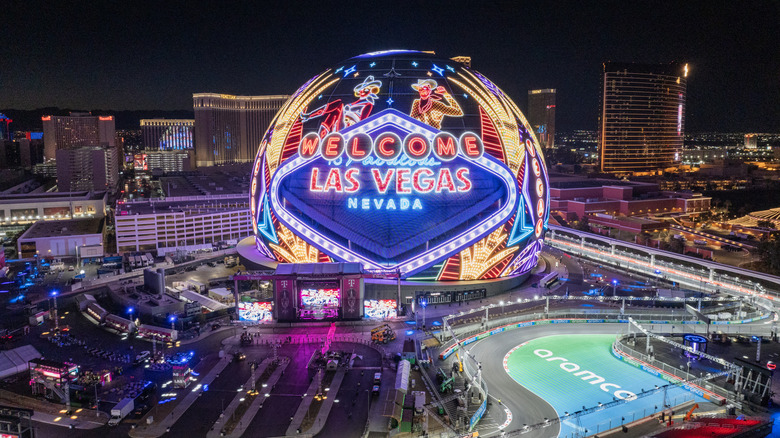 The Las Vegas Sphere at night with the Fabulous Las Vegas sign design on it, surrounded by the megaresorts of The Strip in the background.