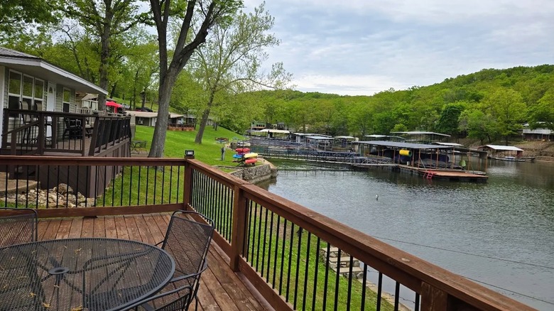 Views from a deck at a waterfront rental in Laurie, Missouri, featuring a scenic cove, boat docks, and lush greenery in the backdrop.