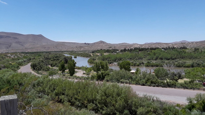 Panoramic view of vegetation, mountains, and a river under a clear blue sky in Leasburg Dam State Park.