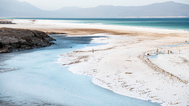 A view of lake Assal in Djibouti with people harvesting salt.