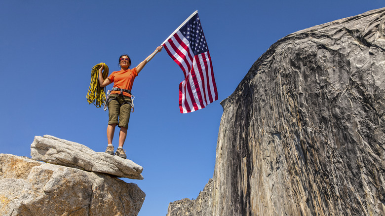 Climber waving an American flag atop a rock formation
