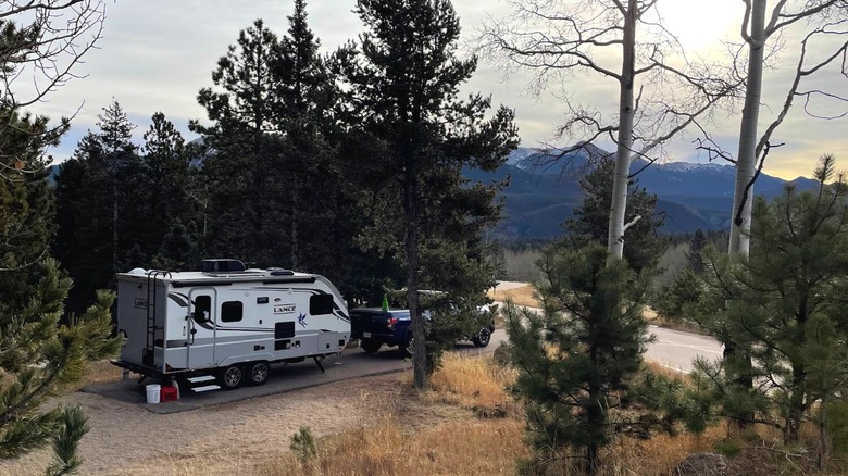 A truck and camper parked within the forested campgrounds of Mueller State Park overlooking the mountains