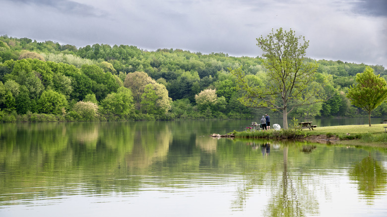 A pair of visitors stands on a peninsula on an overcast day at Lake Arthur, Pennsylvania