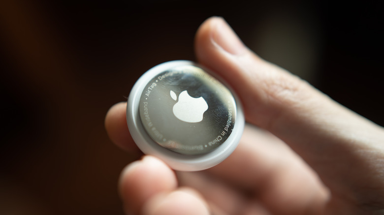 close-up of a hand holding an Apple AirTag