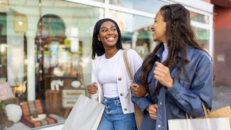 Two friends walking and holding shopping bags