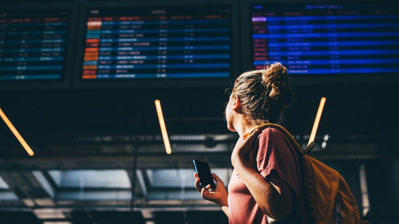 Woman looks at flight board in airport