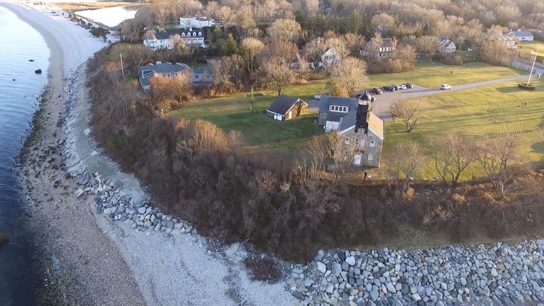 aerial shot of green grass below lighthouse sunny day