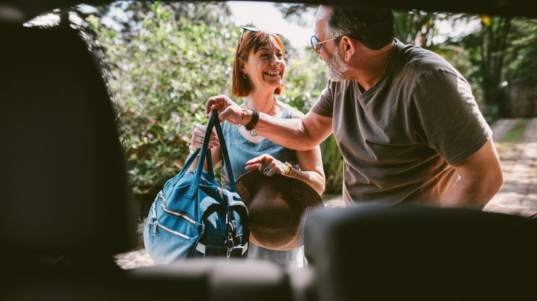 Couple packing travel backs into the trunk of their car
