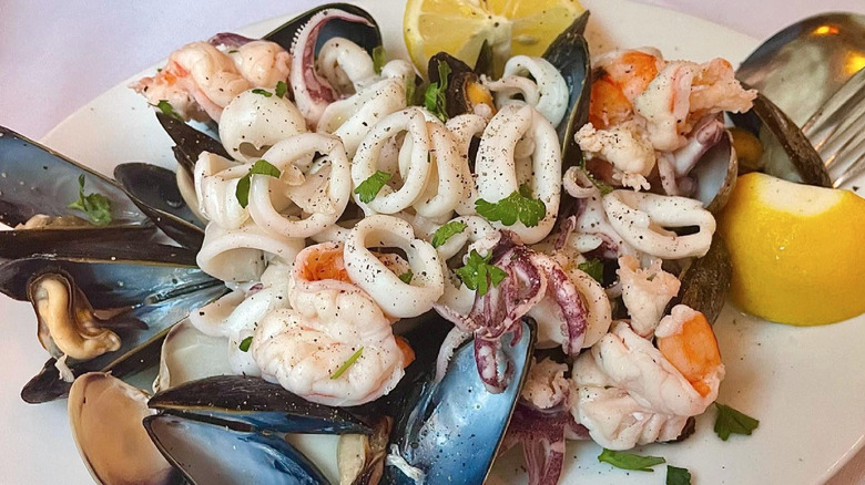 Plate of calimari and other shellfish with lemon wedges and parsley