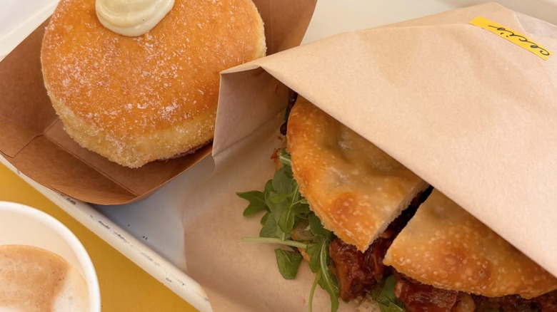 Close-up shot of donut with cream and focaccia sandwich wrapped in paper