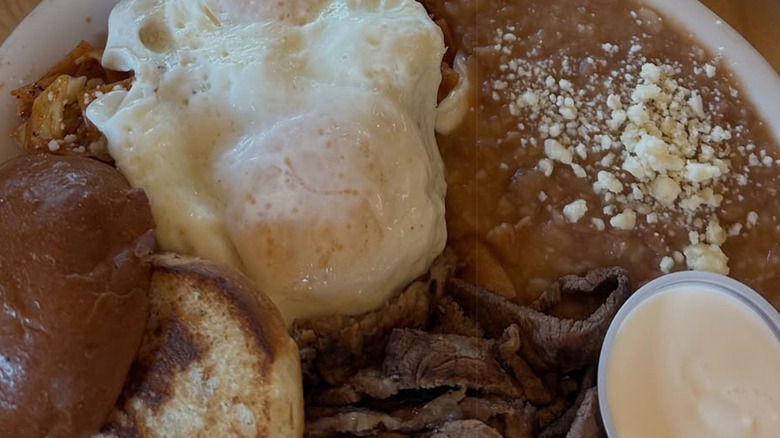 Platter of fried eggs and refried beans with meat and sauce