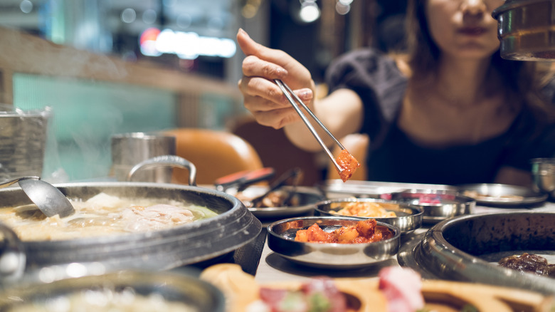 Woman using chopsticks to eat at a Korean barbecue