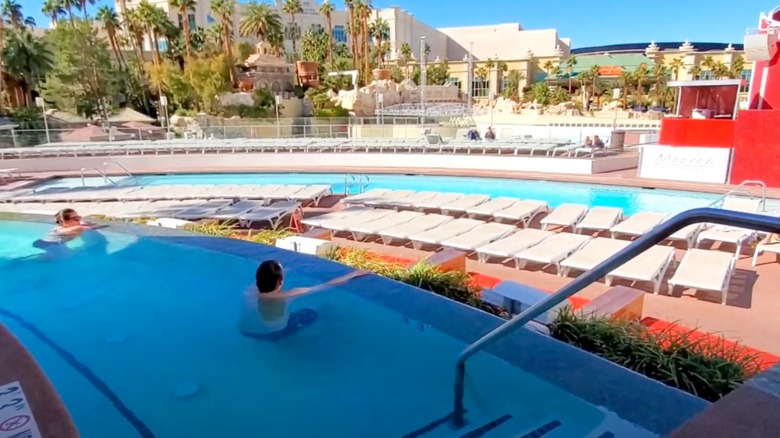 Two people in Moorea Beach Club pool overlooking sun beds and hotel in background