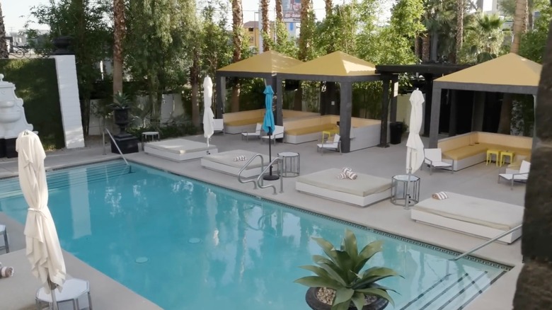 View of an empty pool at The Lexi Hotel in Las Vegas surrounded by cabanas, day beds, and closed parasols