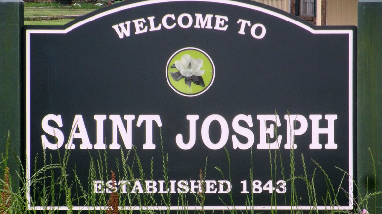 Black-and-white "Welcome to Saint Joseph" sign with a picture of a white flower on it