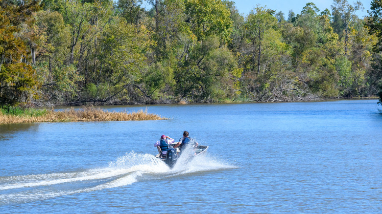 Two people on a boat on the water near Lake Fausse Pointe